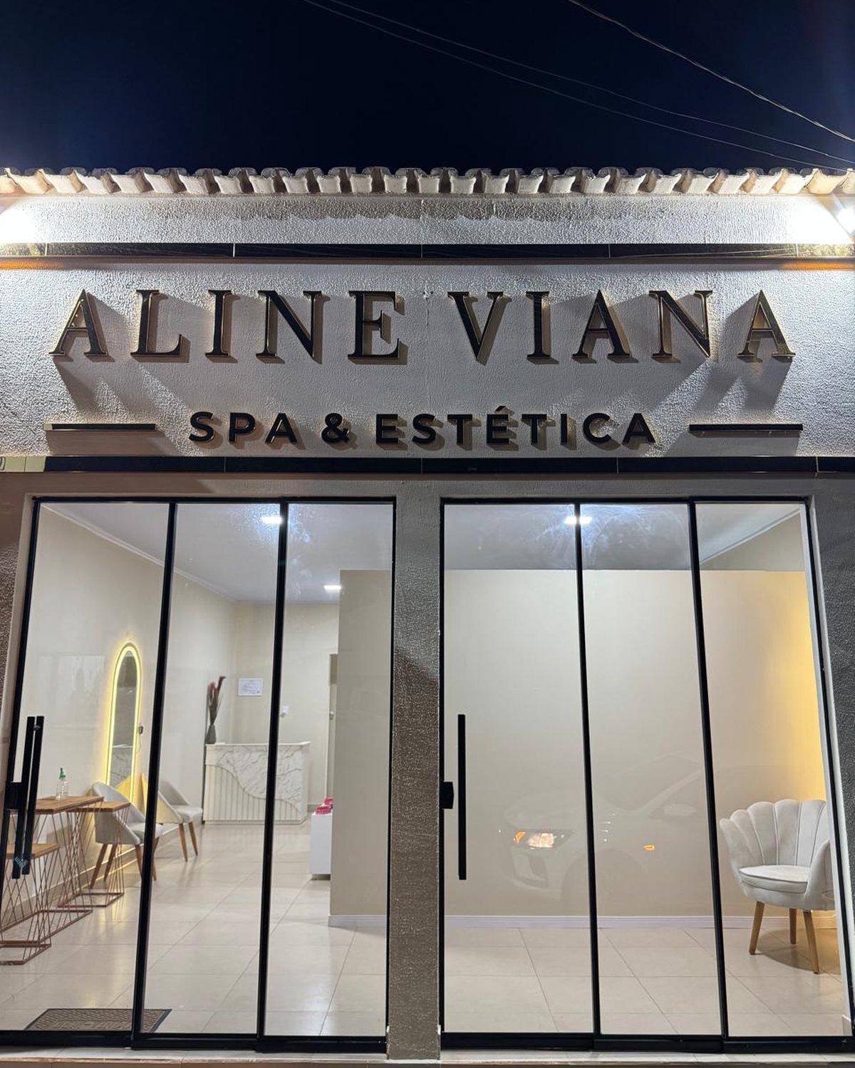 Fachada da clínica à noite com letreiro iluminado.